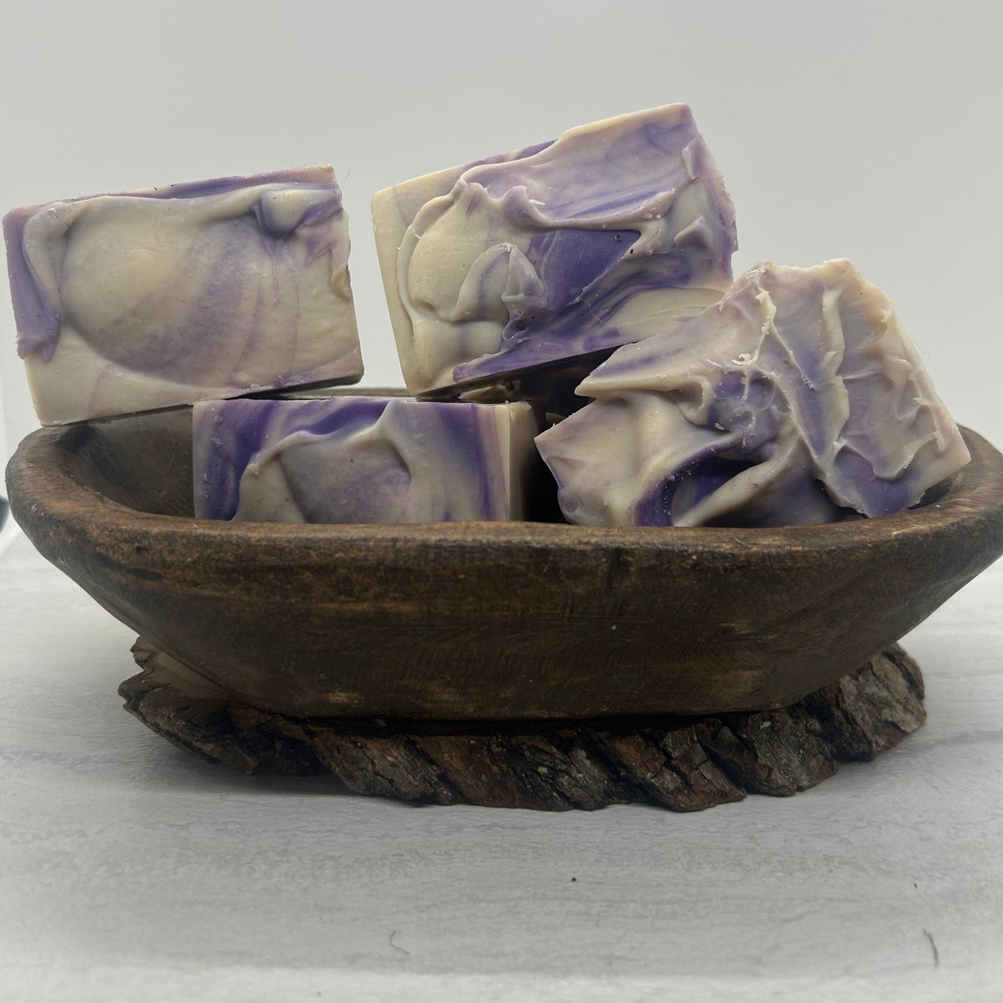 Lavender goat milk soap bars in a wooden bowl