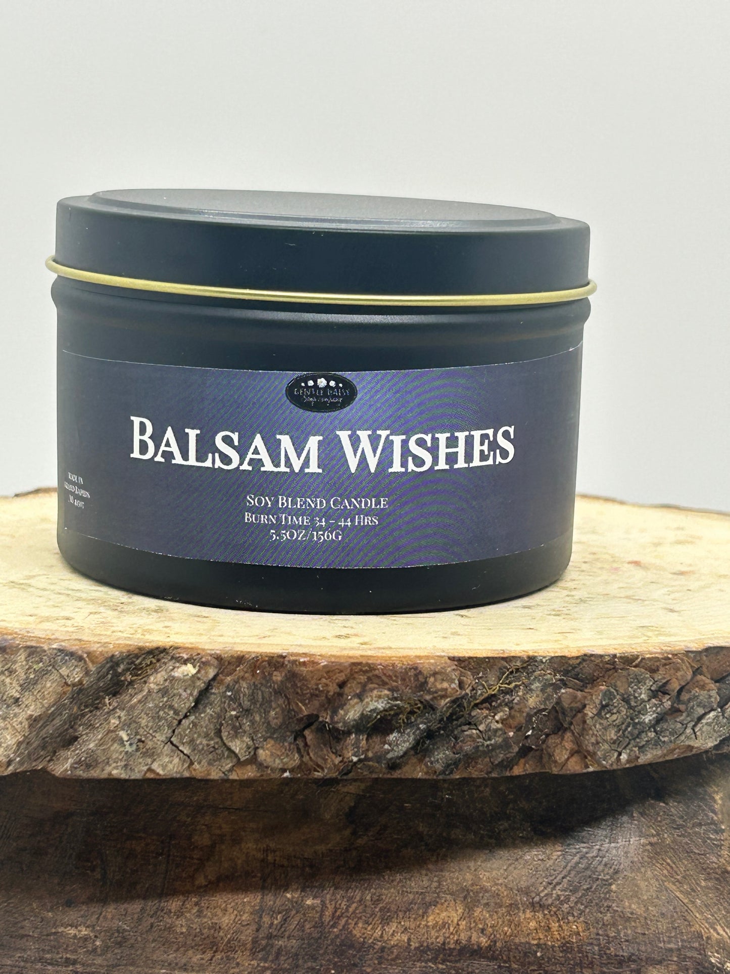 Balsam Wishes candle tin on a wooden surface with a gray background