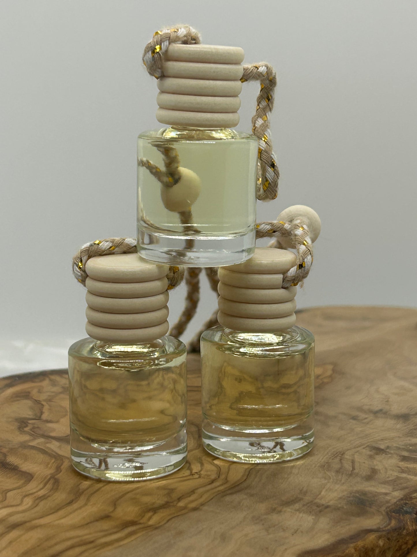 Three small glass bottles with beige stoppers on a wooden surface. Car Diffusers