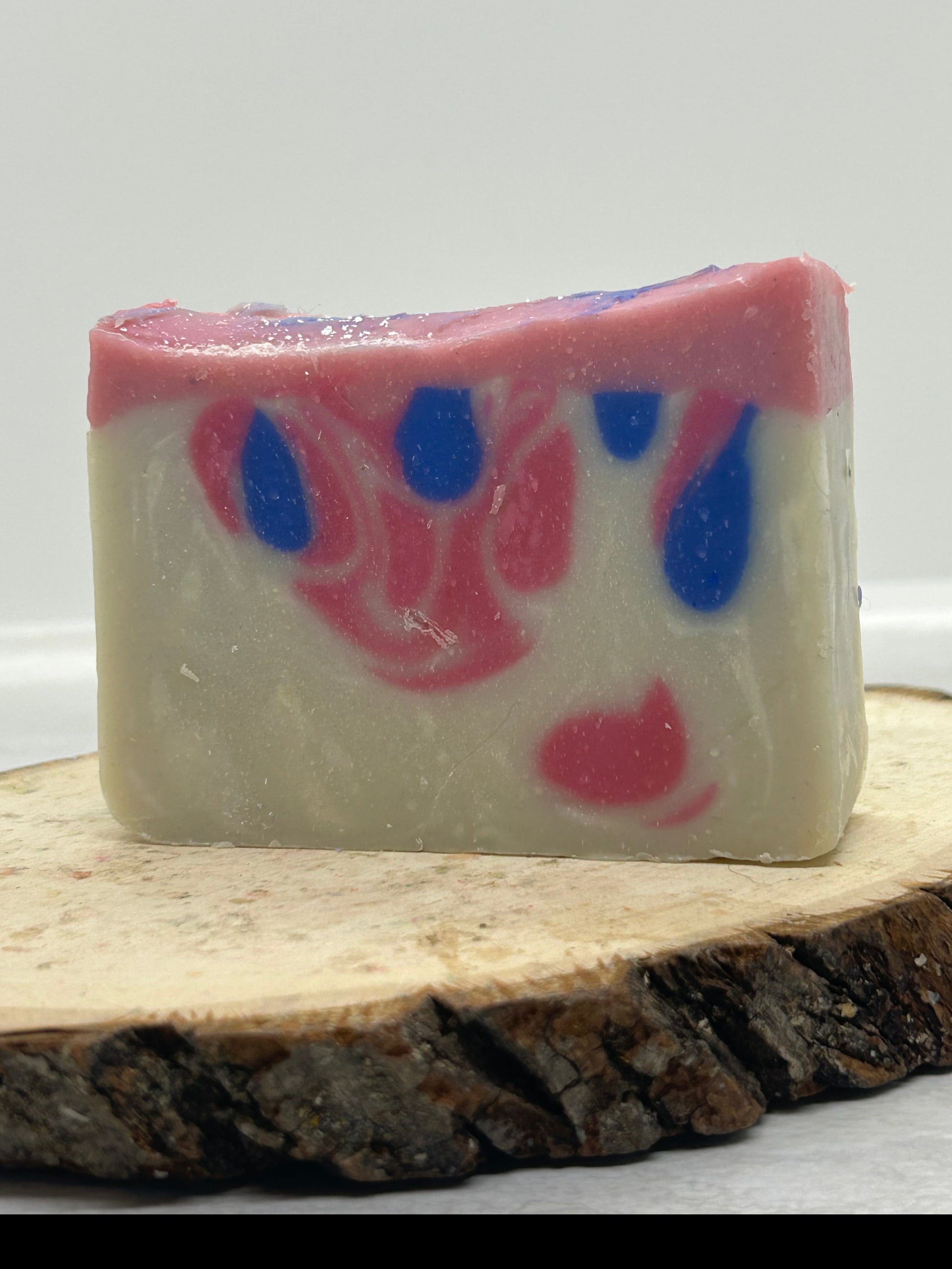 Bar of soap with pink and blue swirls on a wooden block